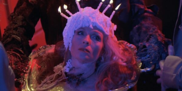 A woman's head on a platter with birthday candles and frosting on her head