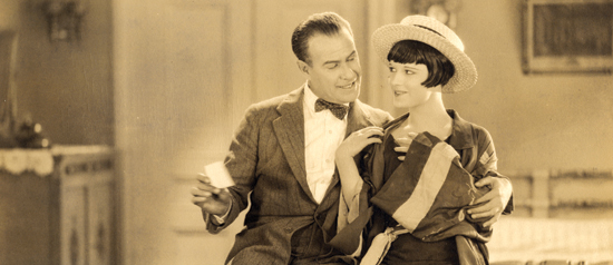 a man and a woman chat with each other in a film still from 1926