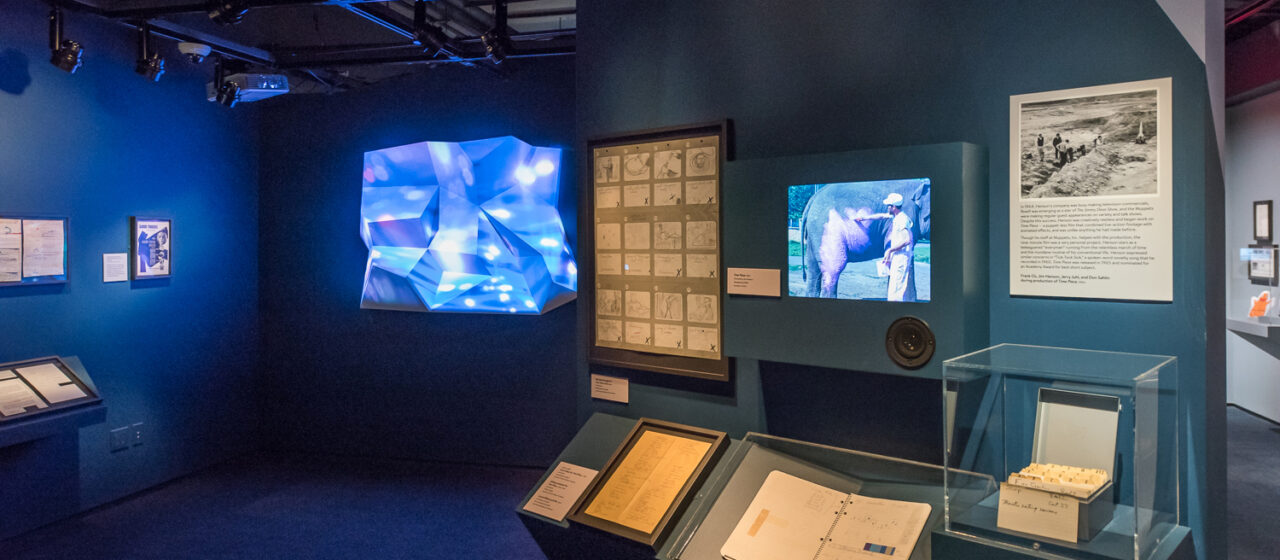 A wall of screens and documents at a museum