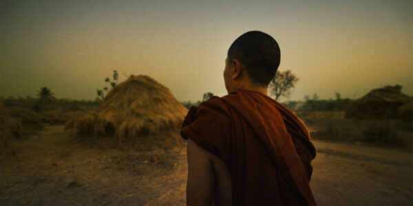 a man in buddhist monk robe faces away from the camera