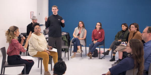 A teacher standing in the middle of a circle of seated learners