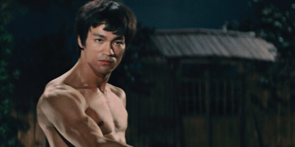 Bruce Lee, standing in a martial arts pose, shirtless