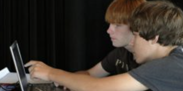 Two teens pointing at a computer