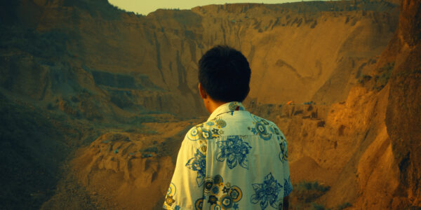 A man in a print shirt looks away from the camera towards a quarry