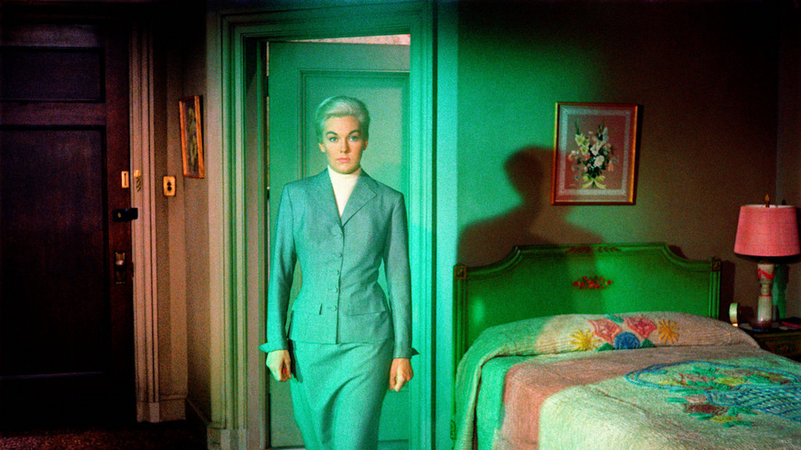 Woman in a gray suit in a green room looking at camera