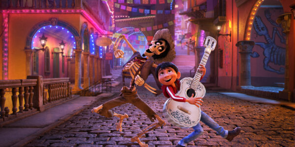 An animated image of a boy and a skeleton with a guitar singing a song on a street in Mexico