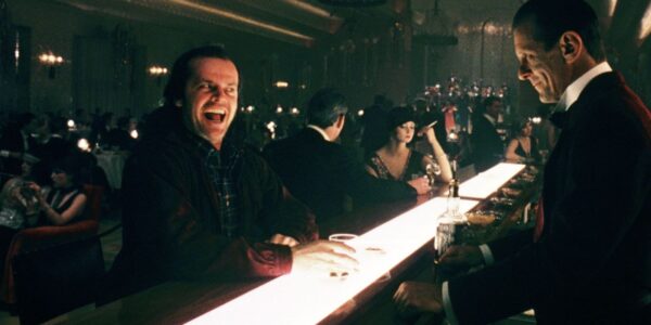 A deranged man smiling while sitting at a bar
