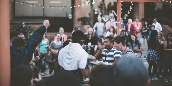 Teenagers playing a game and smiling outdoors while surrounded by other young spectators