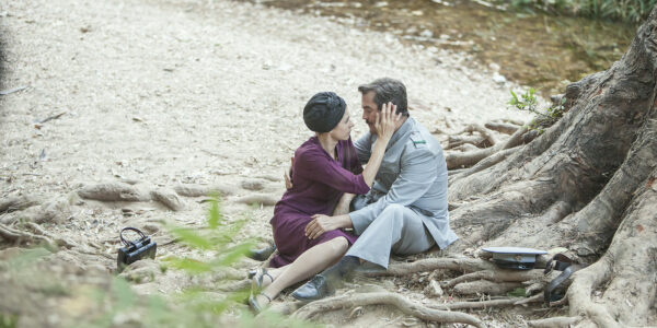 A man and a woman embrace sitting on the ground in a park