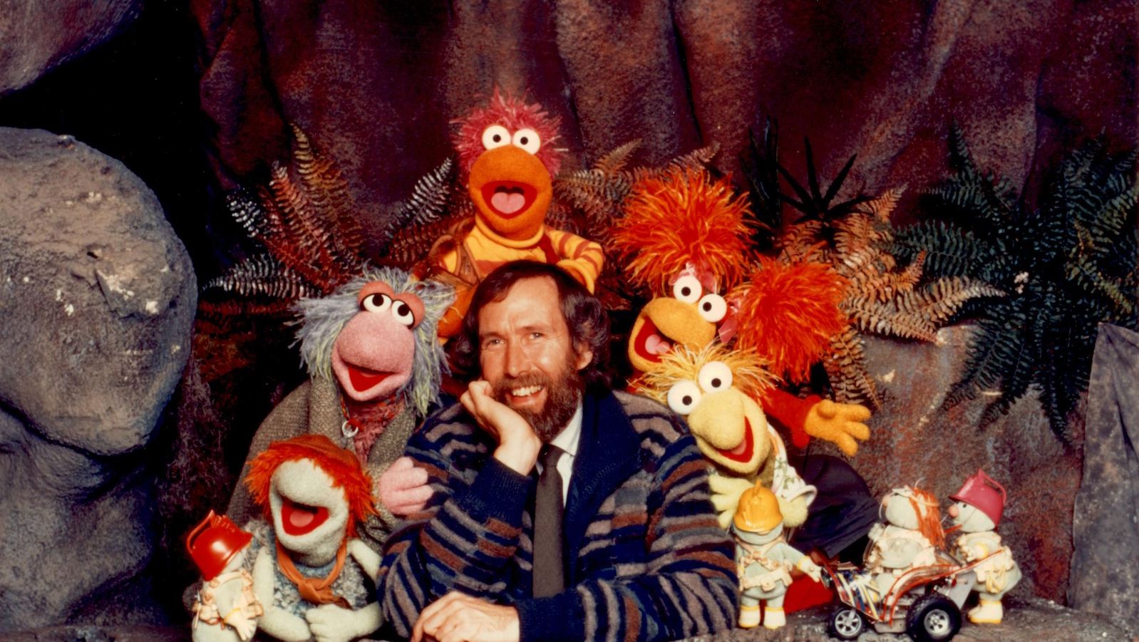Jim Henson surrounded by his Fraggle puppet creations, all looking at the camera.