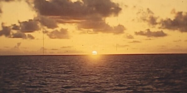 A sun sets on the yellow horizon across an expanse of sea.