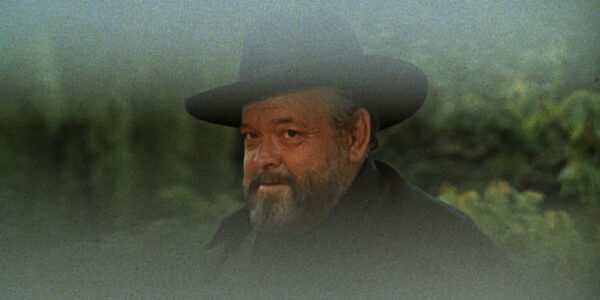 A bearded man surrounded by fog grins at the camera