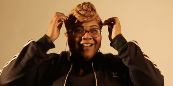 A woman adjusts her hair and smiles into the camera