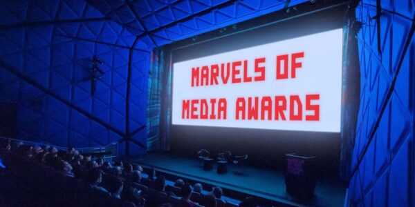 A theater showing a screen saying MARVELS OF MEDIA AWARDS in red font