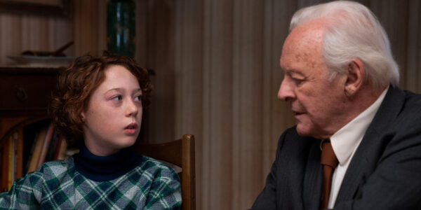 A young boy and his grandfather look at each other at the dinner table.