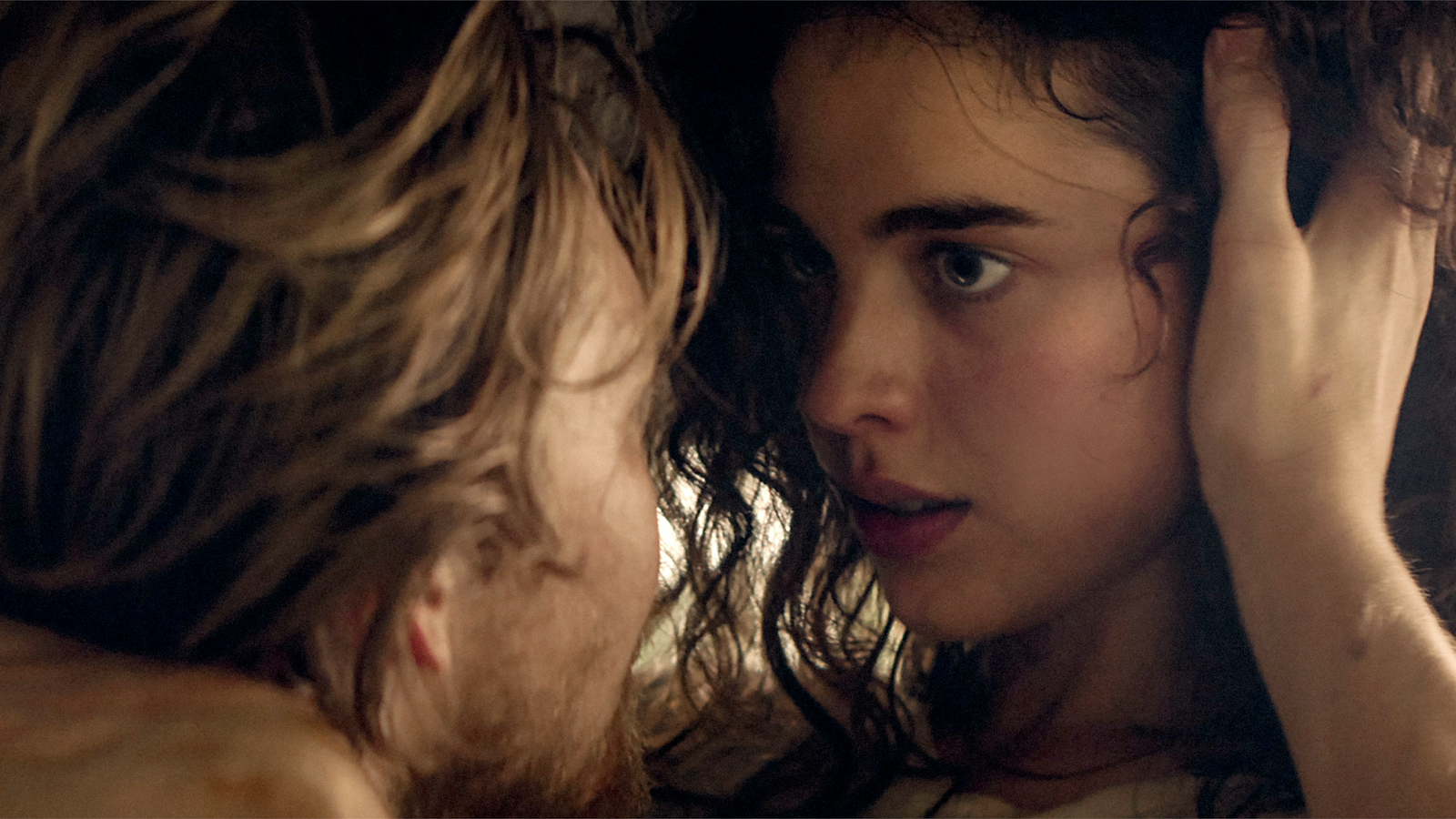 A man holds a woman's head, pushing her hair back from her head