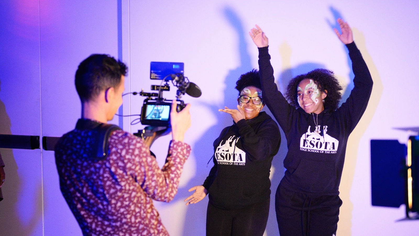 Two young women in facepaint joyously dancing in front of a camera