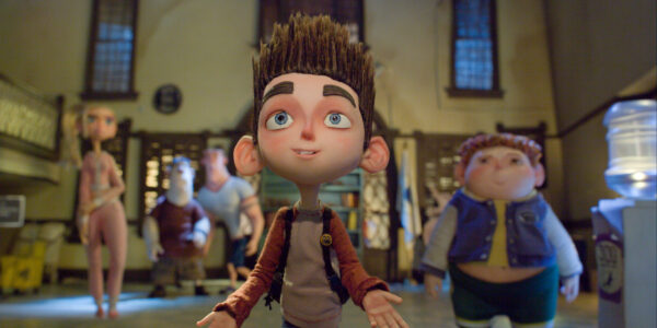 A stop-motion animated boy surrounded by his friends in the background, looking up towards the camera