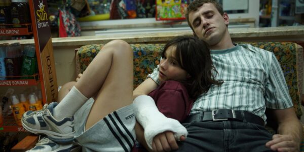 A man in an arm cast holding a young girl as they recline on a couch