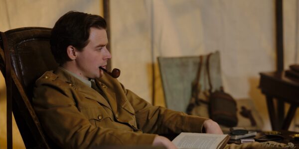A man sits in a tent smoking a pipe