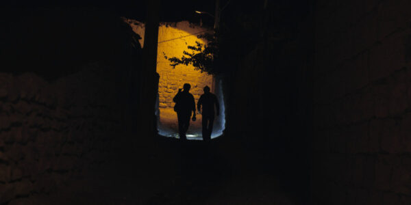 Two people silhouetted in dark nighttime street