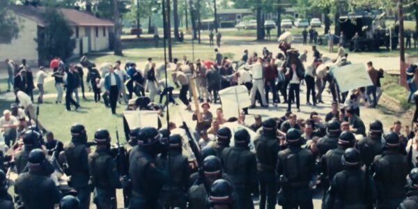 Groups of people in riot gear standing in front of protestors.