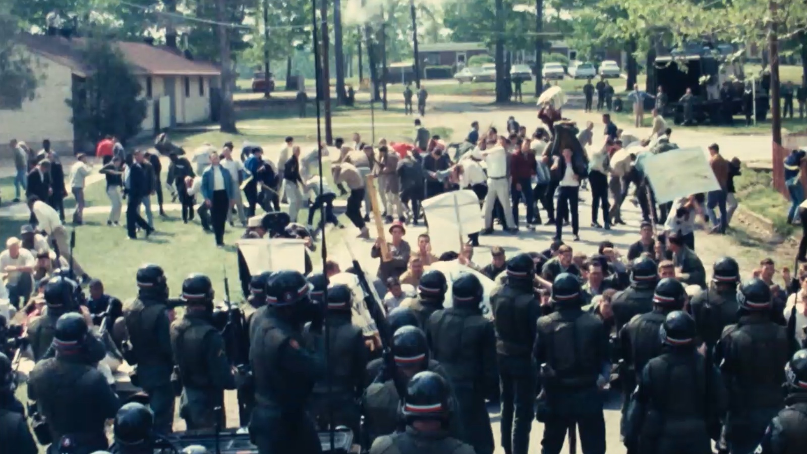 Groups of people in riot gear standing in front of protestors.