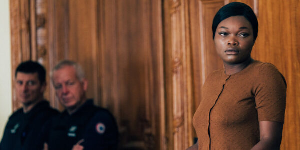 A woman in beige stands in a courtroom