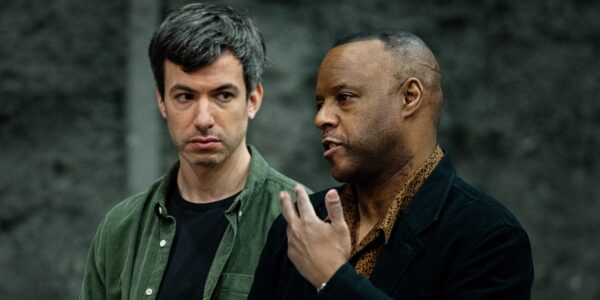 Two men in conversation, one in foreground talking, the other looking at him intently