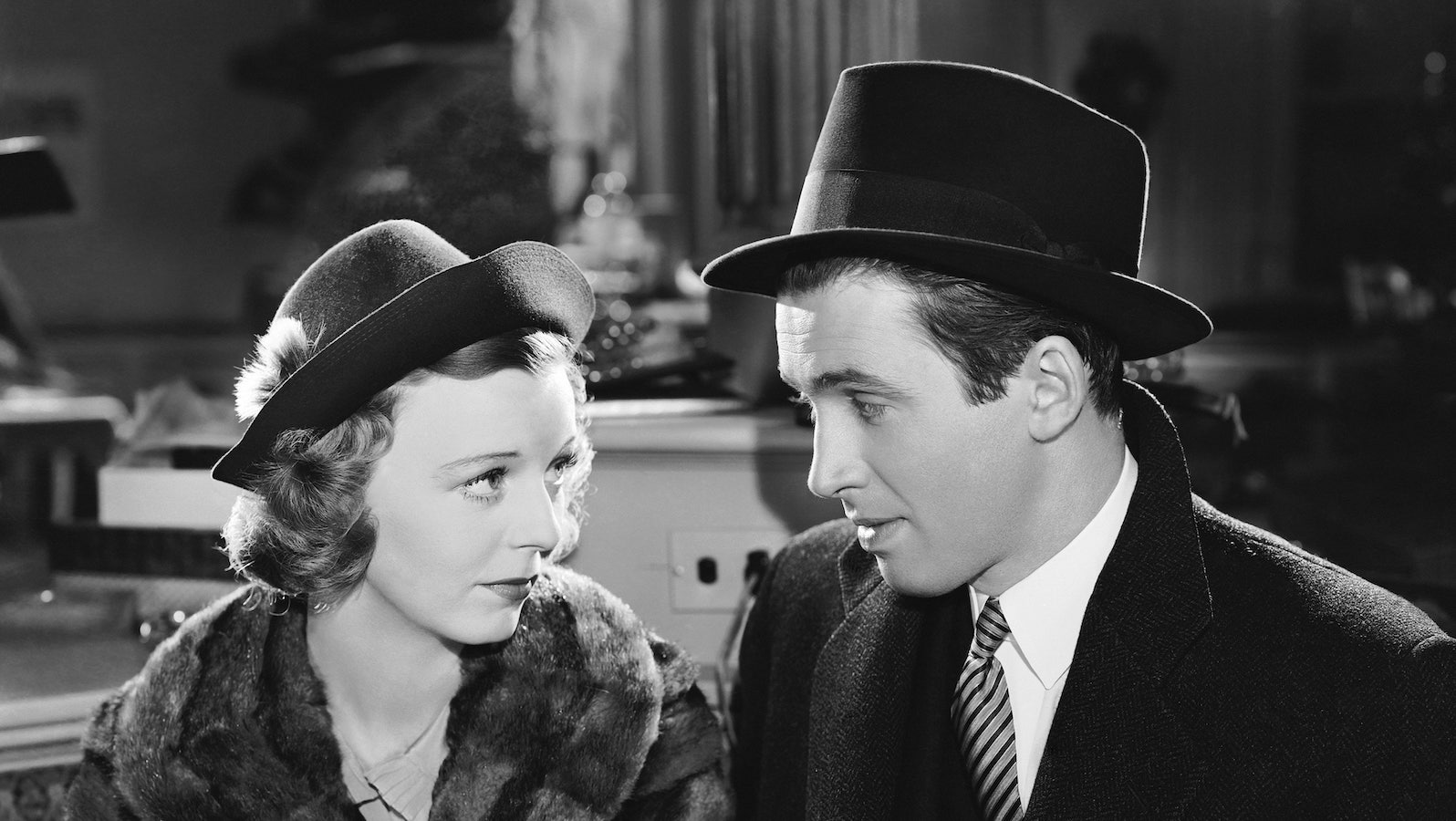A man and a woman in hats sitting in restaurant looking at each other
