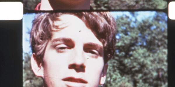 A close-up of a man on 16mm color film looking into camera.