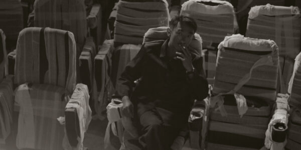 A black and white image of a man sitting in a seat in an empty theater