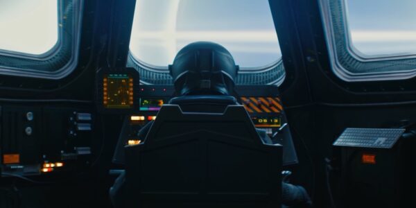 An image of a helmeted pilot in a spaceship, seen from behind, looking out a front windshield