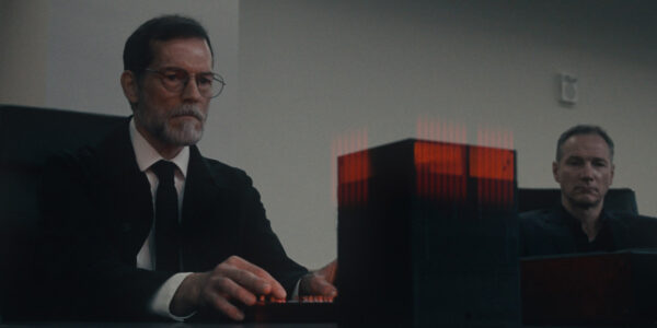A man sits in front of a red box on a table