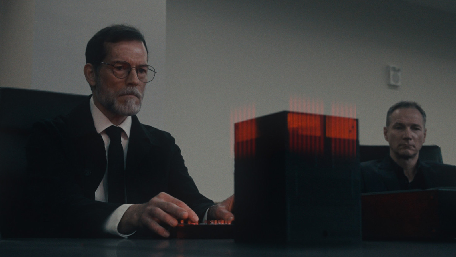 A man sits in front of a red box on a table