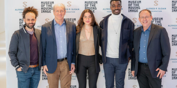 Five people stand in front of a step-and-repeat that features logos for Museum of the Moving Image and Alfred P. Sloan Foundation