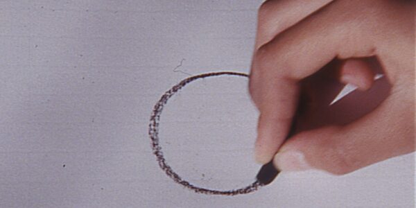 A hand draws a circle on paper