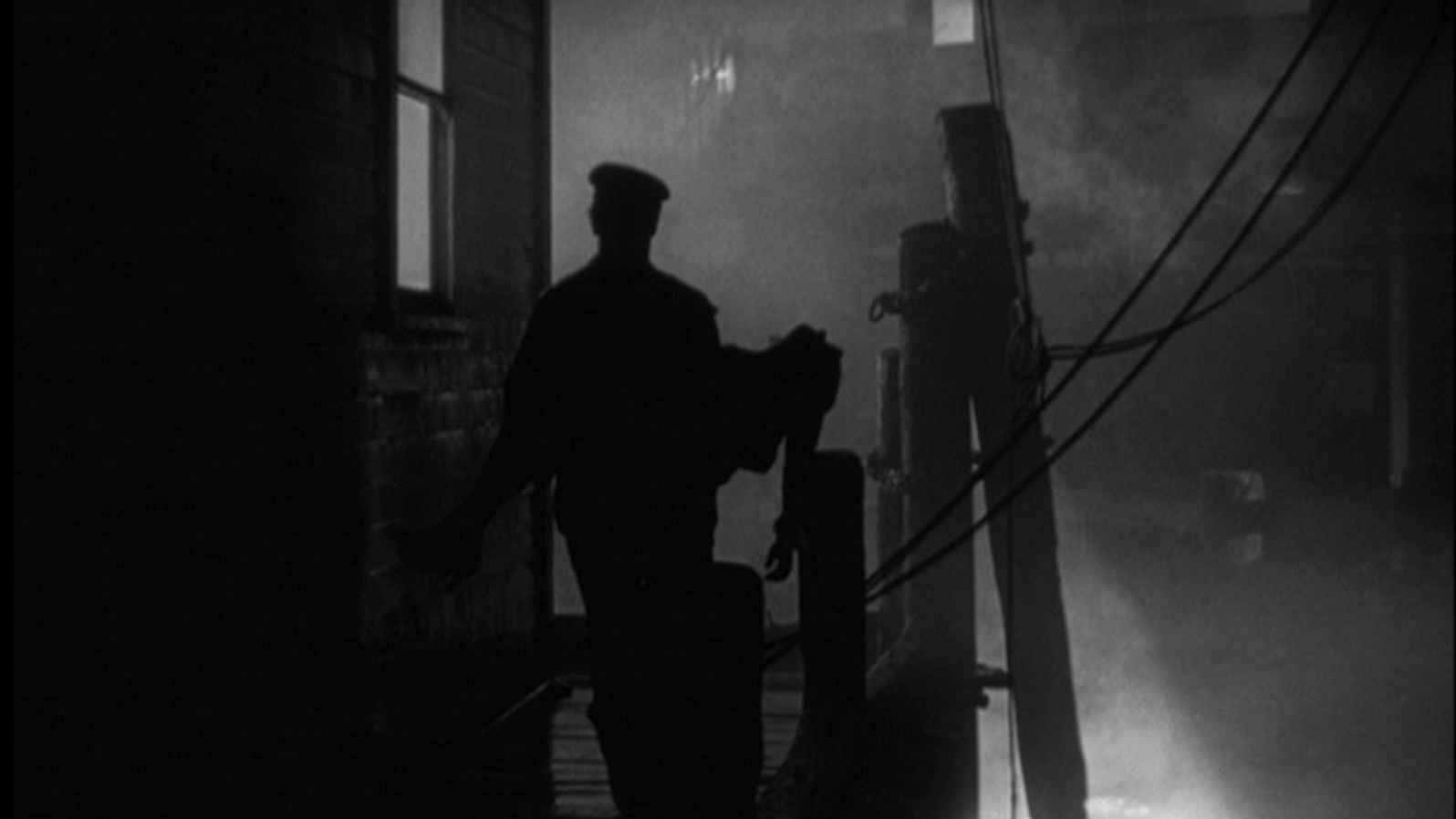 a man in silhouette against a misty dock at night