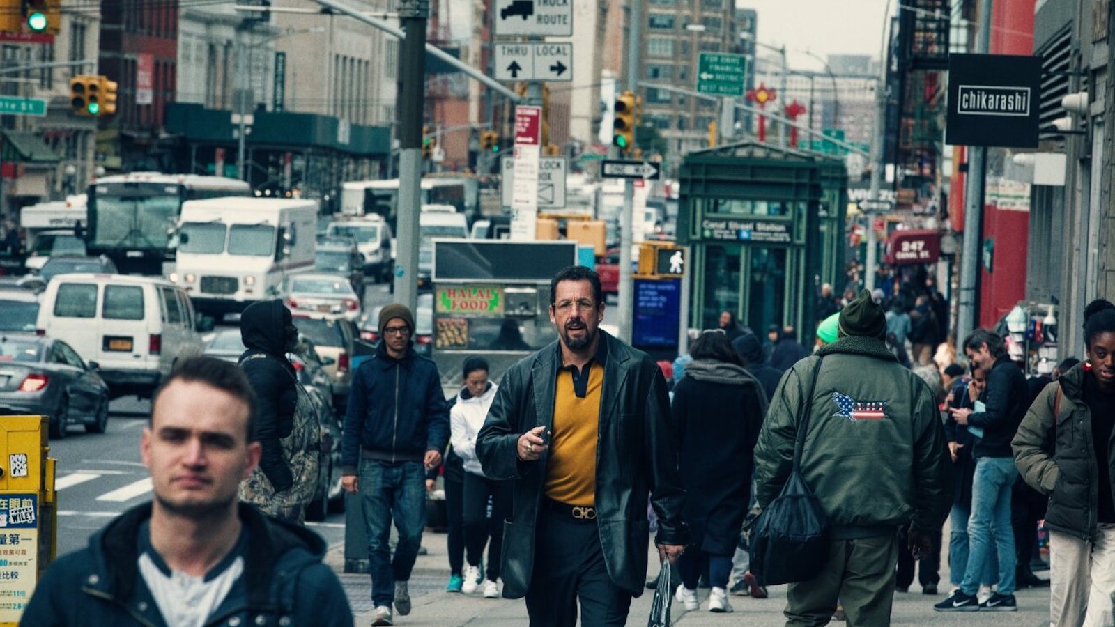 uncutgems A man in yellow shirt and blue jacket walks through a crowded midtown NYC street
