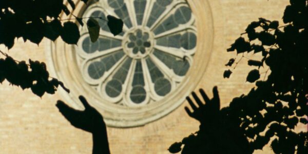 silhouettes of hands reaching for a church window