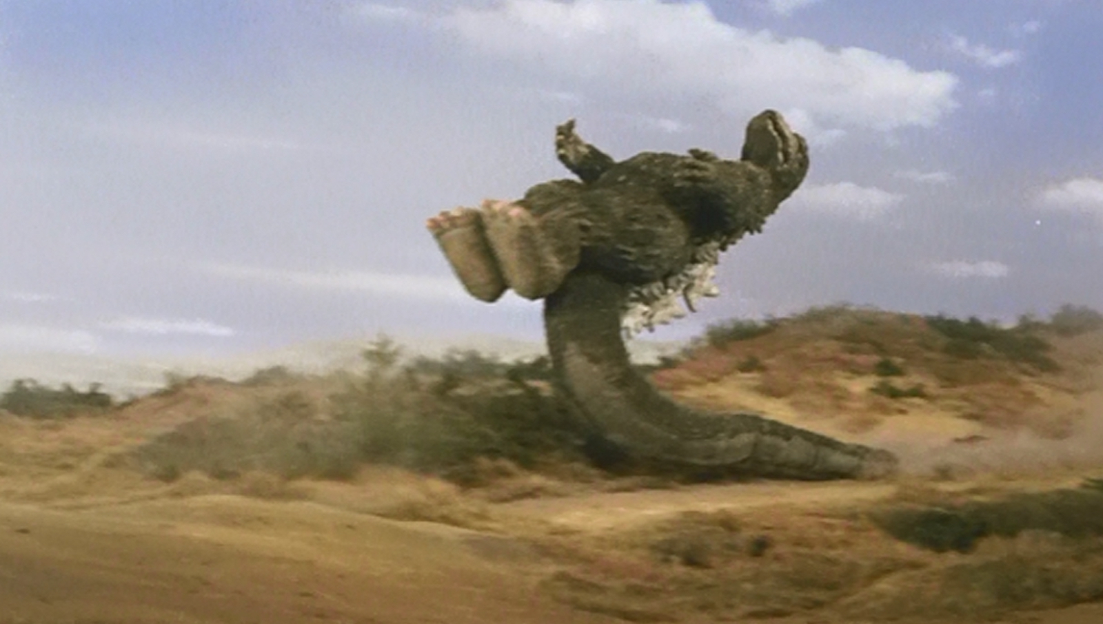 A rubber dinosaur named Godzilla stands upright on its tail