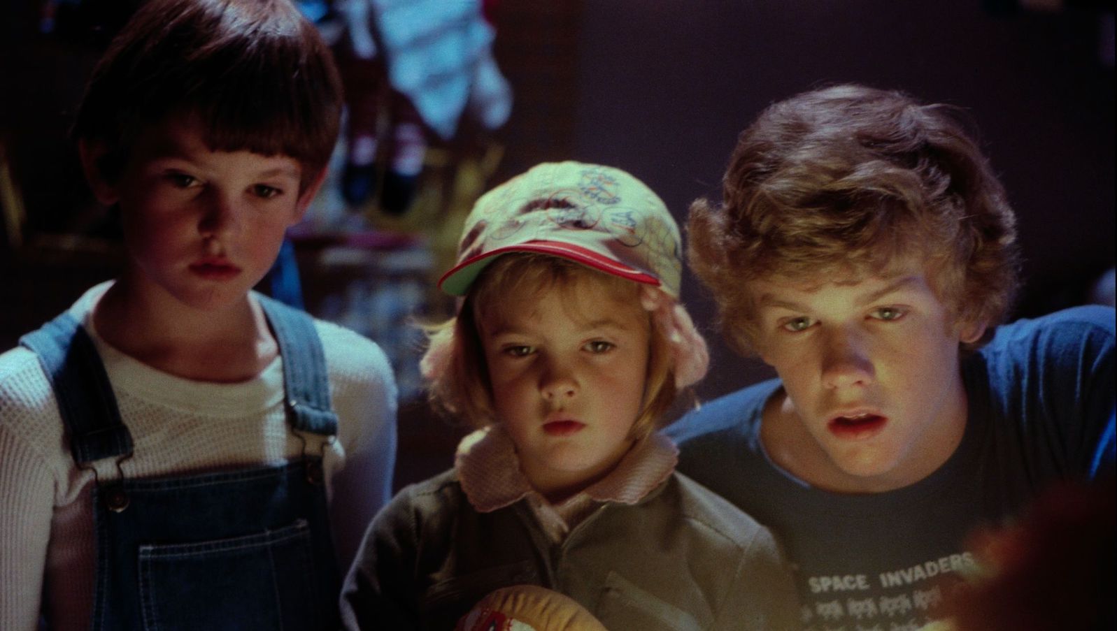 Three kids, two boys and a little girl, look in amazement off screen