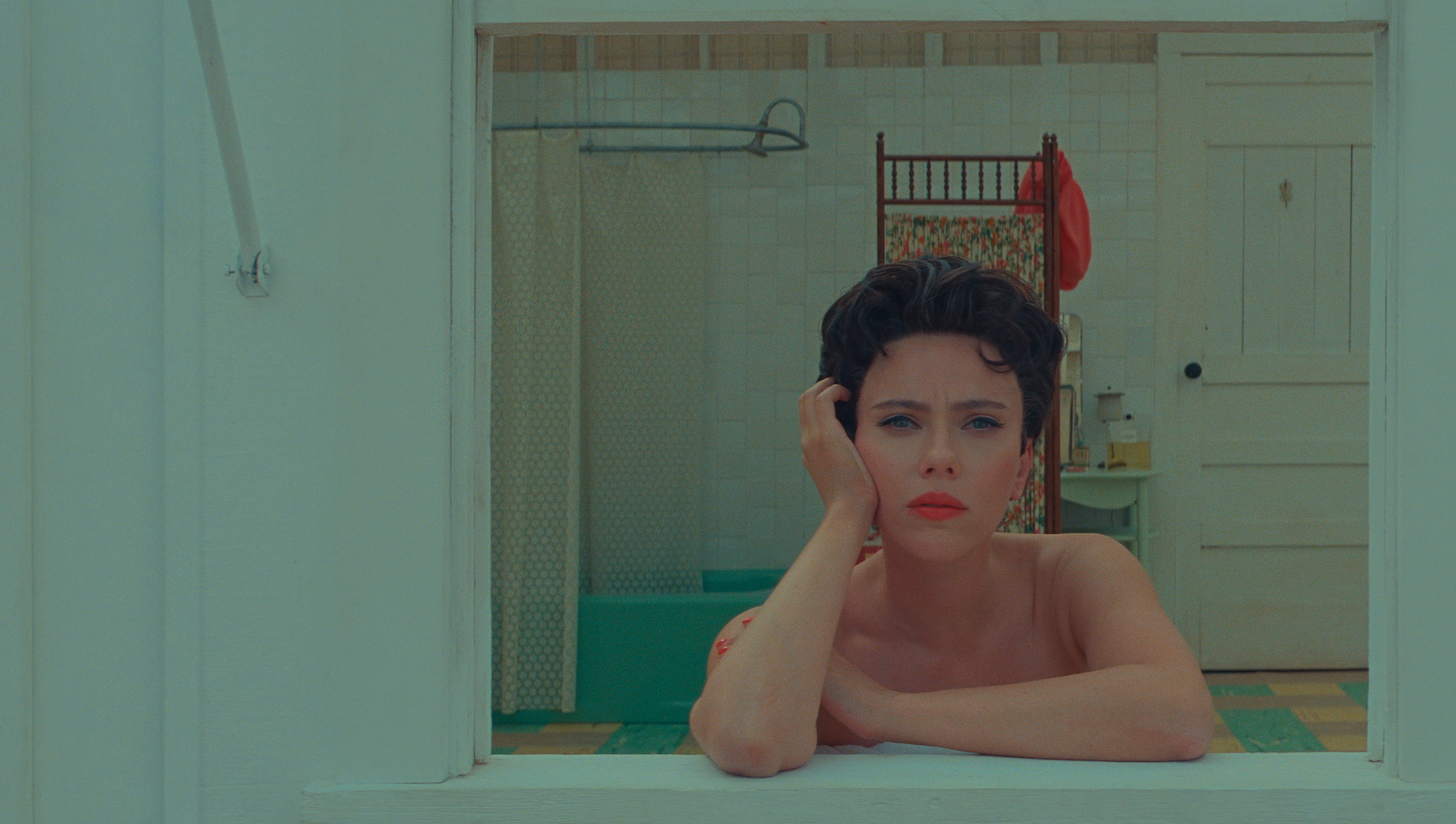 A brunette woman with short hair looks out a window