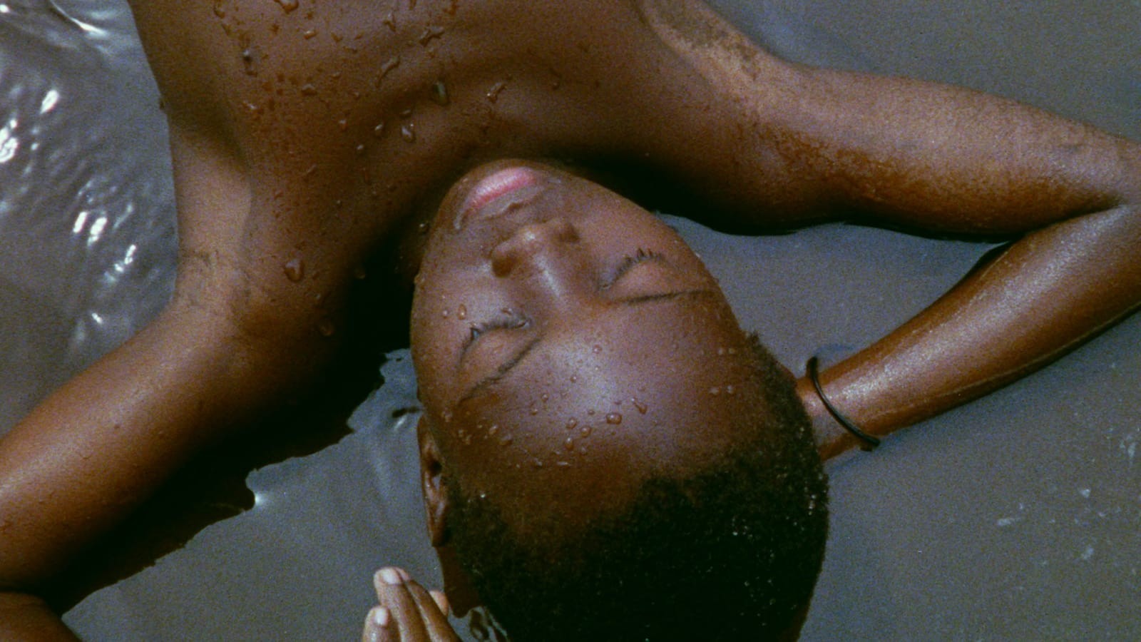 An upside down shot of a little boy, shirtless with his hands rested beneath his head, relaxing