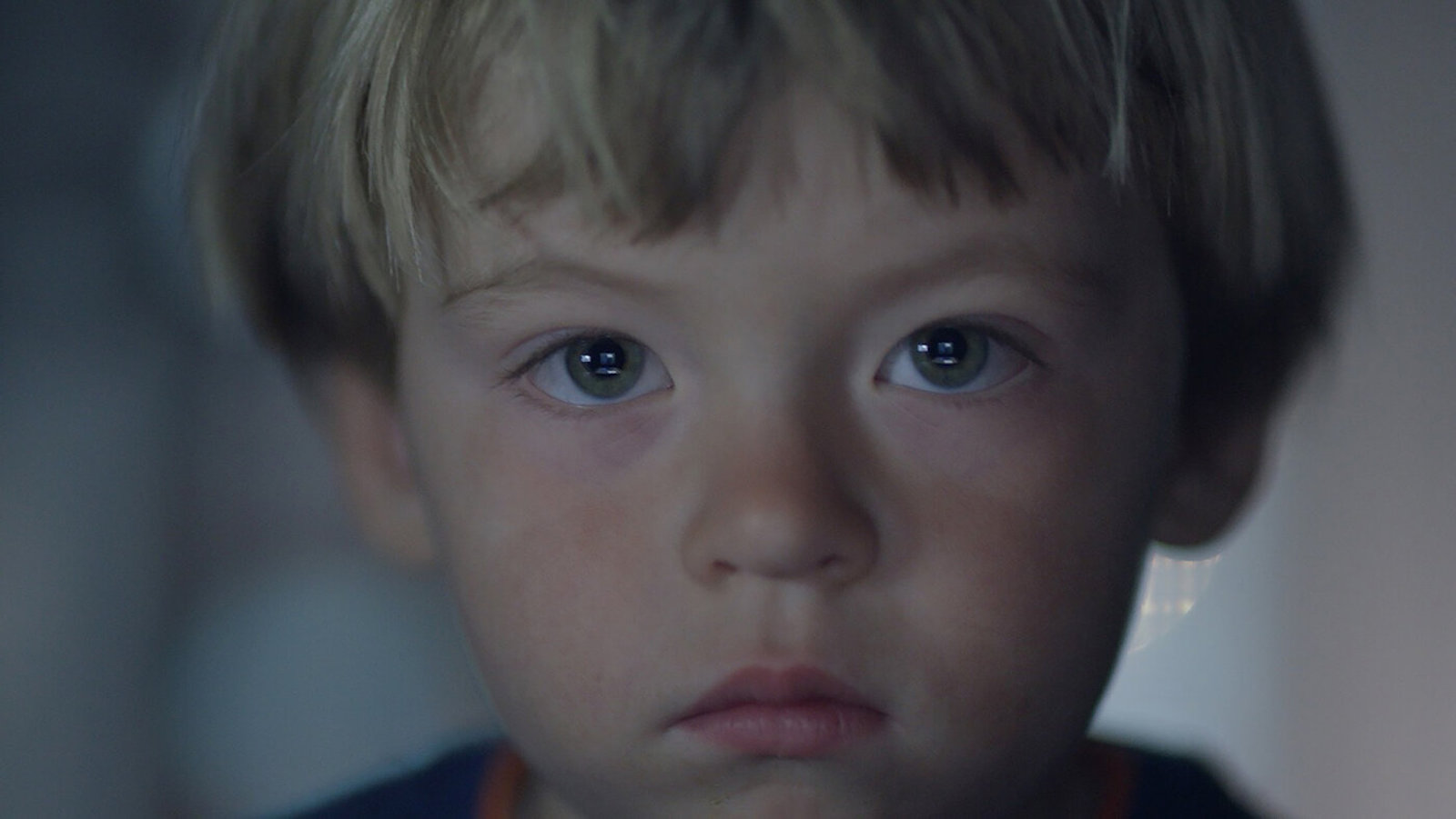 A young blond boy's face in closeup looking at camera