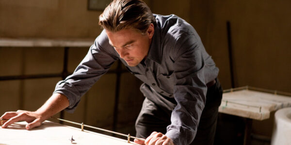 A man leans over a table and intently looks at a spinning top