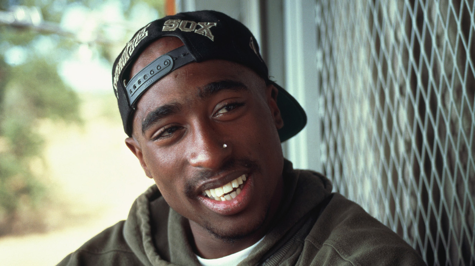 Man in a backwards baseball cap smiles at the camera