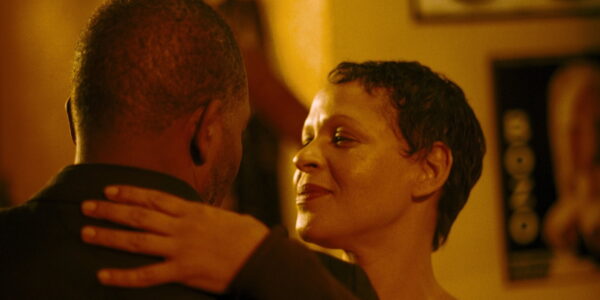 A man and a woman dancing, his head to the camera, she facing it in profile