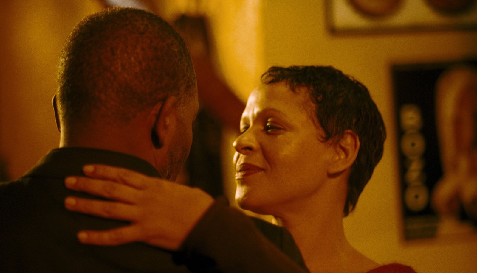 A man and a woman dancing, his head to the camera, she facing it in profile