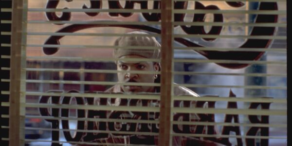 A man looks through the window of a barbershop from outside on the street